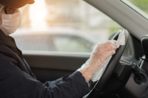 woman wipes truck steering wheel with gloves and mask